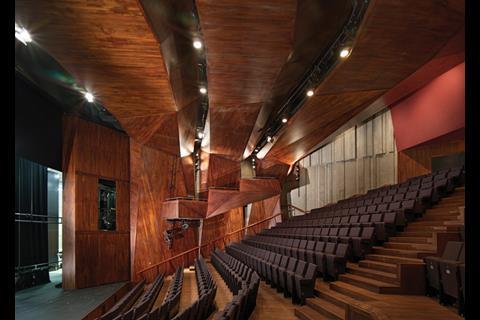 The main auditorium is conceived as a faceted timber grotto, spanned by three lighting arches.